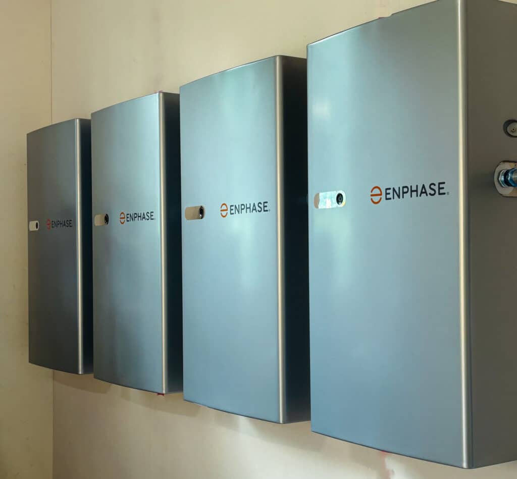 a group of four enphase solar batteries on a wall