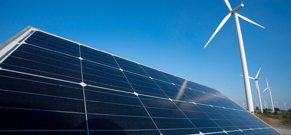 Image of solar panels with wind turbines in the background